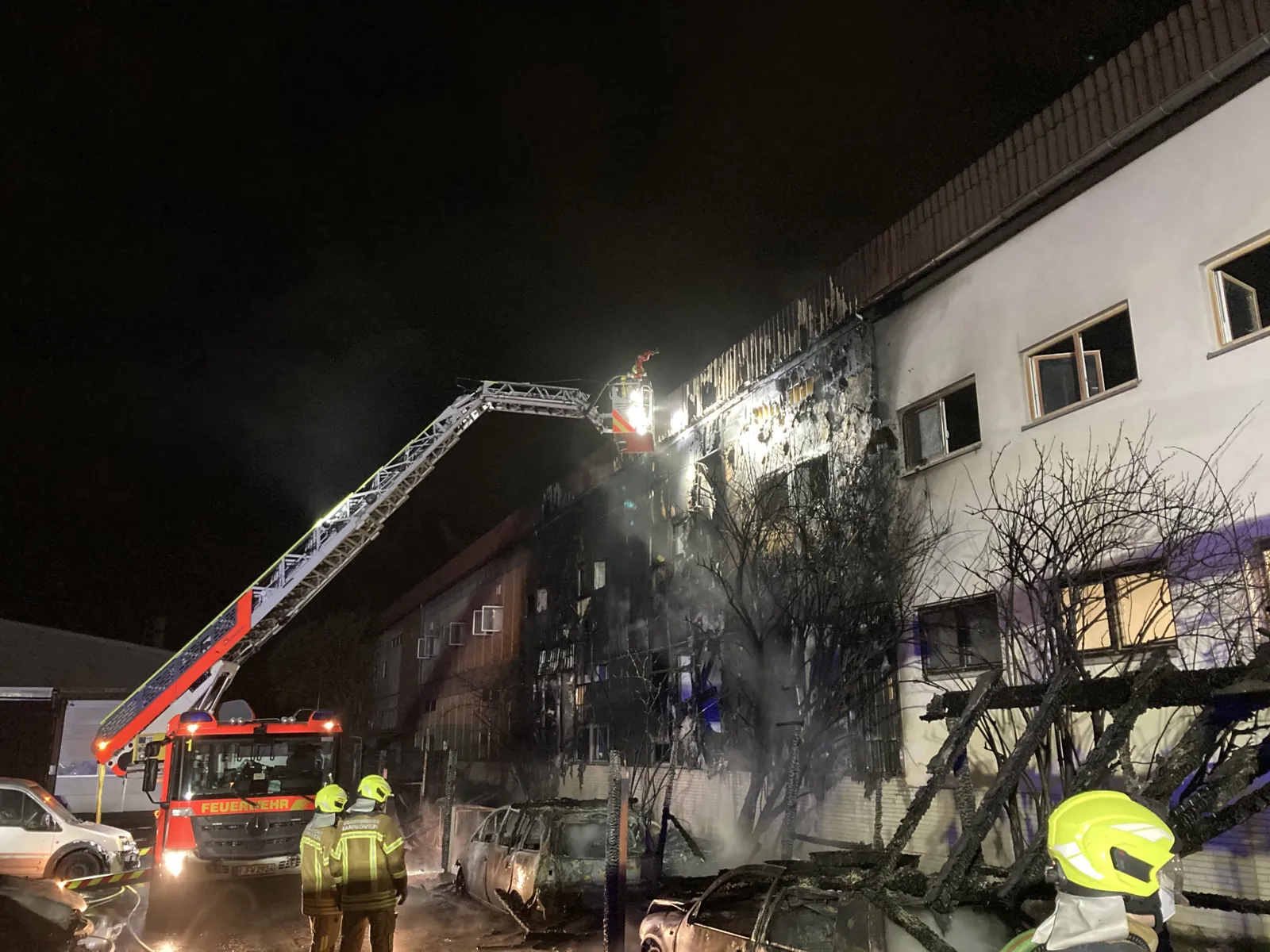 Feuerwehrleute stehen vor einem verbrannten Haus
